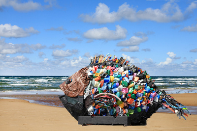 Eine Plastikskulptur eines Fisches vor einem Strand