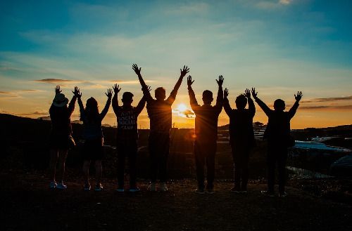 Konfis mit erhobenen Händen vor dem Sonnenutergang