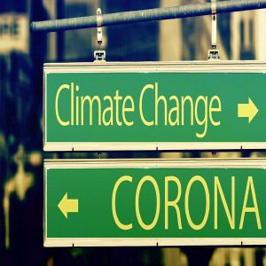 Zwei Straßenschilder, eines weist den Weg zum Klimawandel das andere zu Corona